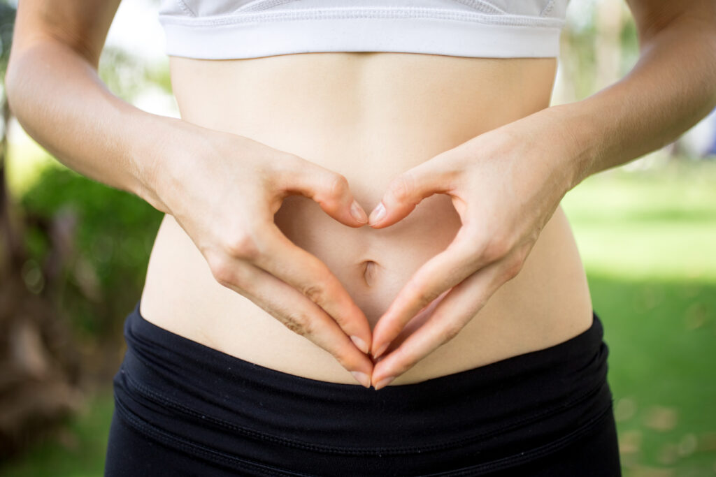 Close-up of female hands shaping heart on belly outdoors. Fitness and dieting concept Źródło: Freepik drżenie które leczy